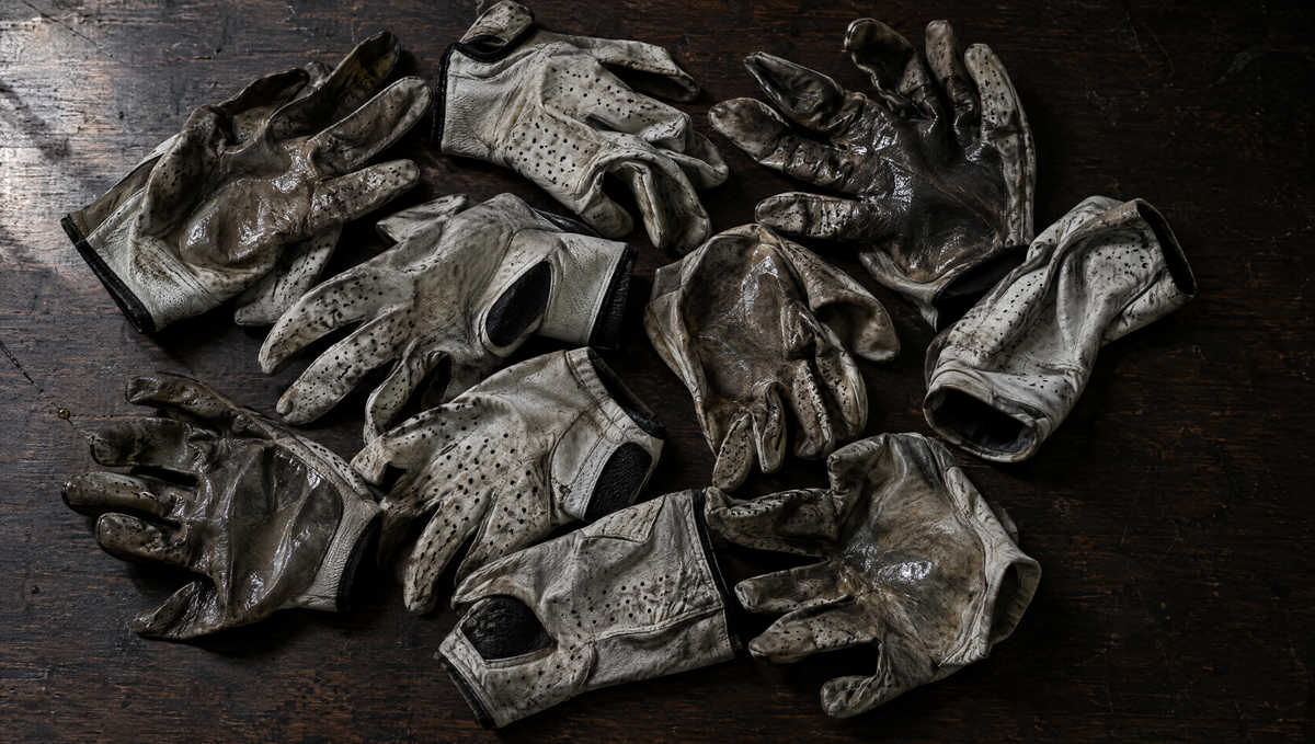 Nine worn-out golf gloves piled on a table
